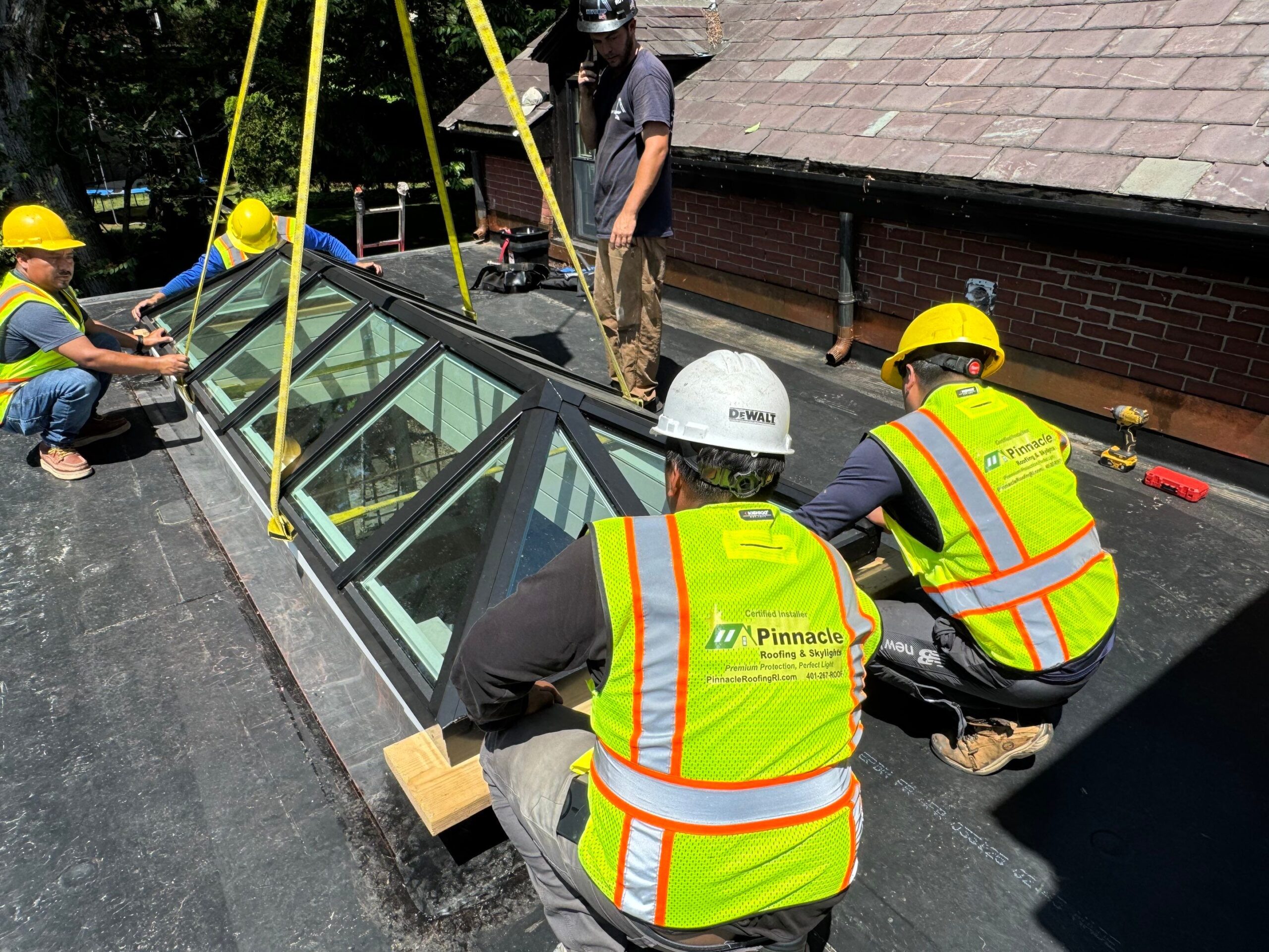 Crew installing a large VELUX metal-framed commercial skylight; crane straps visible during roof placement in Rhode Island